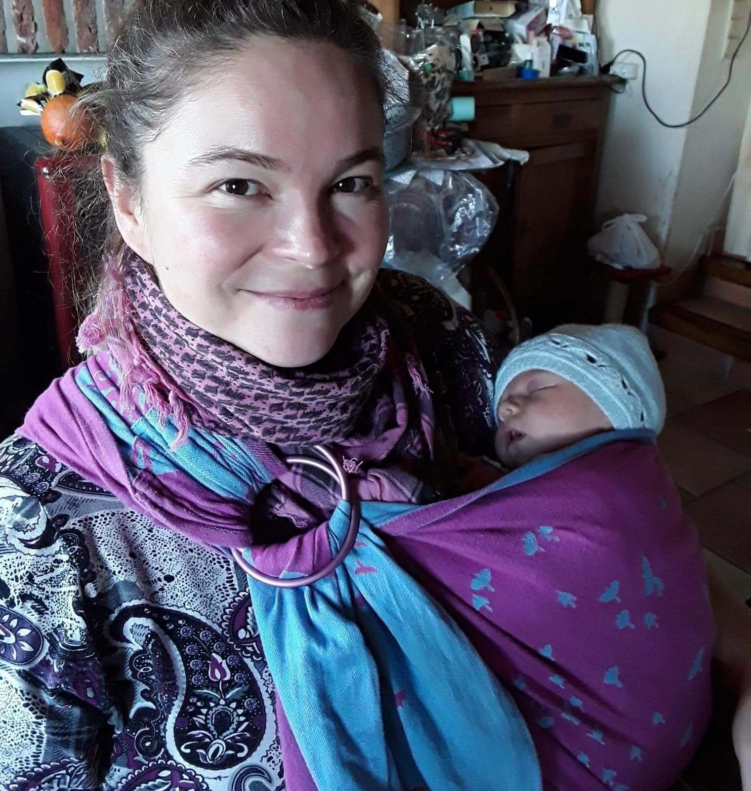 maman portant son nouveau-né dans un sling rose et bleu